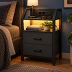 Chevet noir à deux tiroirs avec éclairage LED au chevet du lit.