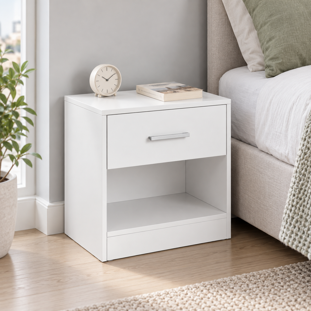 Chevet blanc compact près d’un lit dans une petite chambre.