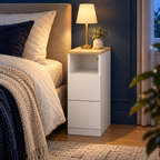 Chevet étroit blanc dans une chambre bleu nuit, éclairé en soirée.
