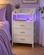 Chevet blanc avec éclairage violet près d’un lit.