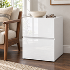 Table de chevet blanche près d’un fauteuil en bois et tissu crème