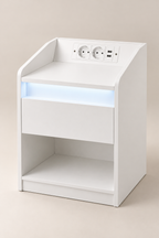 Table de chevet blanche en studio avec éclairage LED sous le plateau.